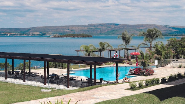A pool area with a view of a lake and hills in the background. - Riviera Capitólio Hotel (Capitólio)