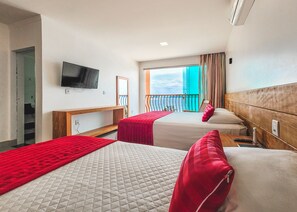 A hotel room with two beds, a TV, a balcony with a view, and a wooden headboard.