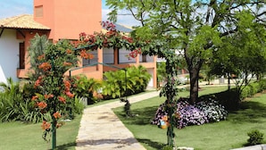 A pathway leading to a building with a tiled roof, surrounded by lush greenery and flowering plants. - Riviera Capitólio Hotel (Capitólio)