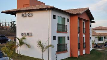 A two-story building with a white facade and orange accents, featuring balconies and air conditioning units.