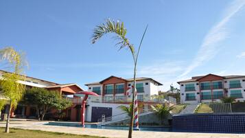 Un edificio moderno con piscina, una sombrilla roja y una palmera.