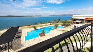 A pool area with a view of a large body of water and distant hills. - Riviera Capitólio Hotel (Capitólio)