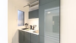 Una cocina moderna con armarios grises, una encimera blanca y una ventana con cortina.