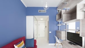 Una sala de estar moderna con un sofá rojo, un televisor y estanterías empotradas.