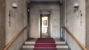 Una escalera con alfombra roja que lleva a una puerta en la parte superior.