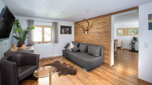 A modern living room with a grey sofa, a leather armchair, and a wooden wall with a mounted deer head. - NEW, EXCLUSIVE, COZY apartment !!!! (St. Gallenkirch)