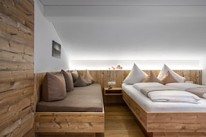 A modern bedroom with a wooden wall, a built-in bench, a bed with pillows, and a bedside table with a remote control. - NEW, EXCLUSIVE, COZY apartment !!!! (St. Gallenkirch)