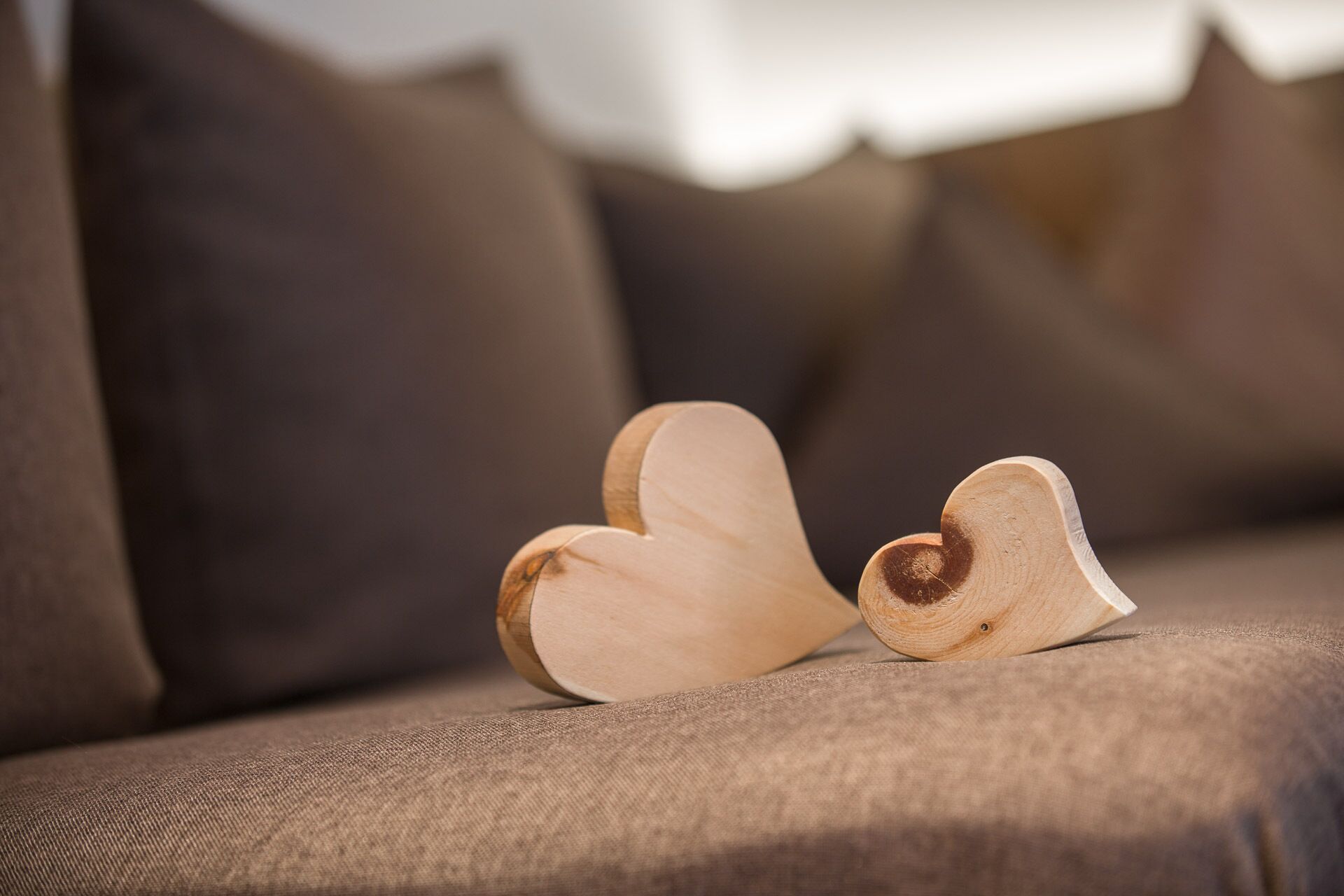 Two wooden heart-shaped objects on a textured brown sofa.