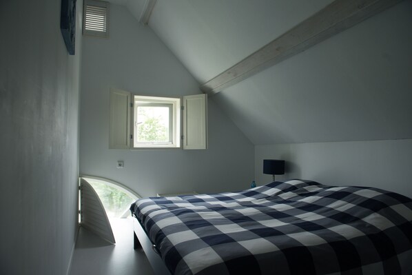 A bedroom with a bed, a window, and a nightstand. - Renovated rural stable near the sea. (Koudekerke)