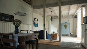A dining area with a wooden table and chairs, a vase of flowers, and a blue chair.