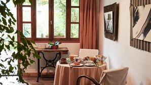 A dining area with a table set for breakfast, a window with curtains, and a plant on the windowsill. - La Foyère (Aime-la-Plagne)