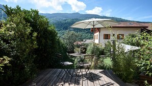 A wooden deck with a table and chairs, a large umbrella, and a view of a mountain landscape. - La Foyère (Aime-la-Plagne)