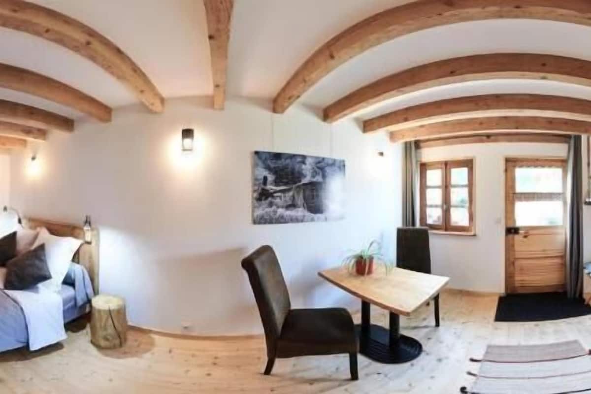 A room with a bed, wooden furniture, a table, and a chair.