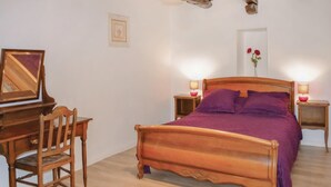 A bedroom with a wooden bed, a desk with a chair, two bedside tables with lamps, and a framed picture on the wall.