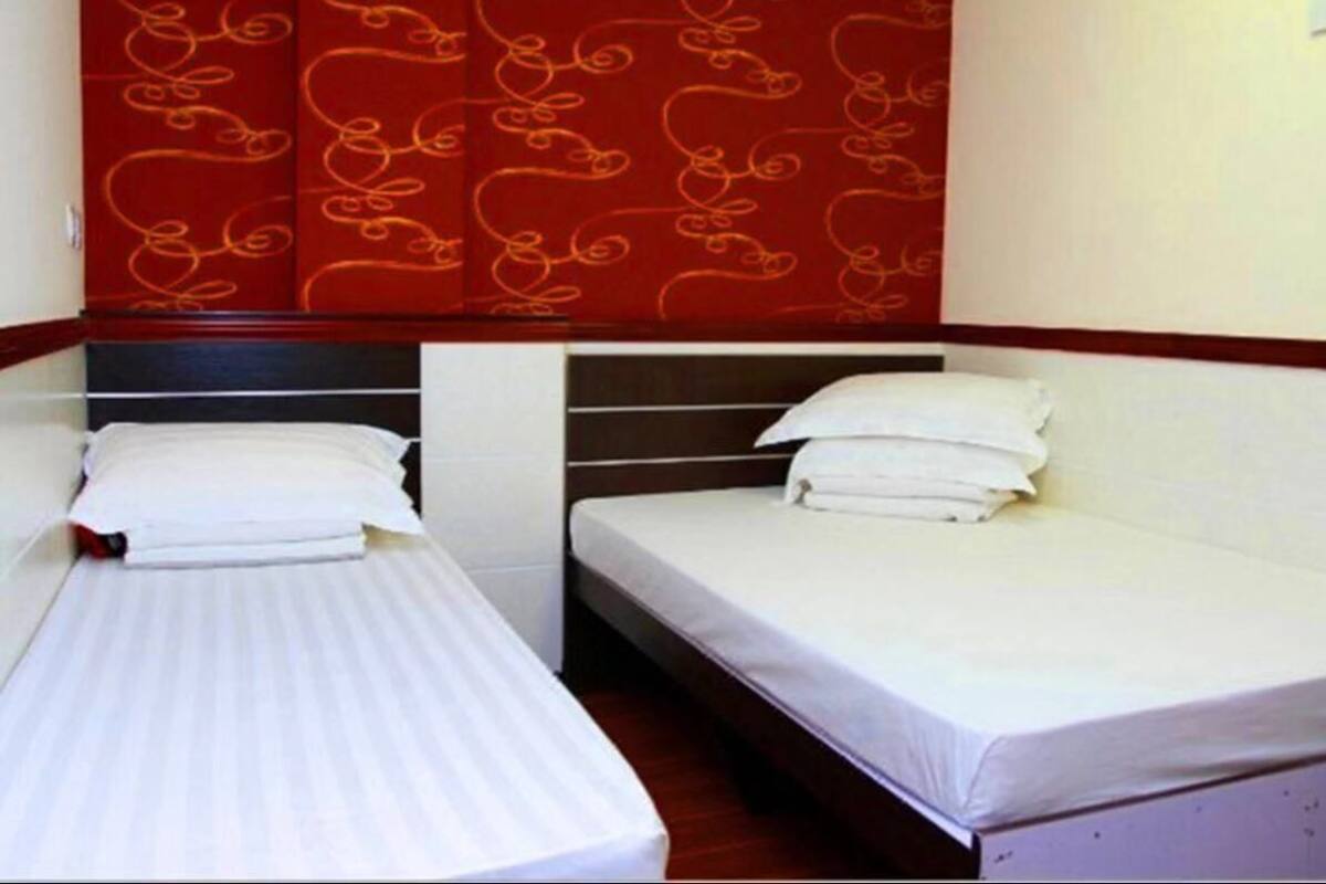 Two single beds with white linens in a room with a red patterned headboard.