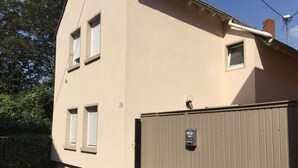 Een beige gebouw met een hekpoort, een klein raam met luiken en een beveiligingscamera.