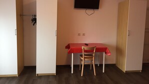 Een kamer met een bureau, een stoel en een aan de muur bevestigde televisie.
