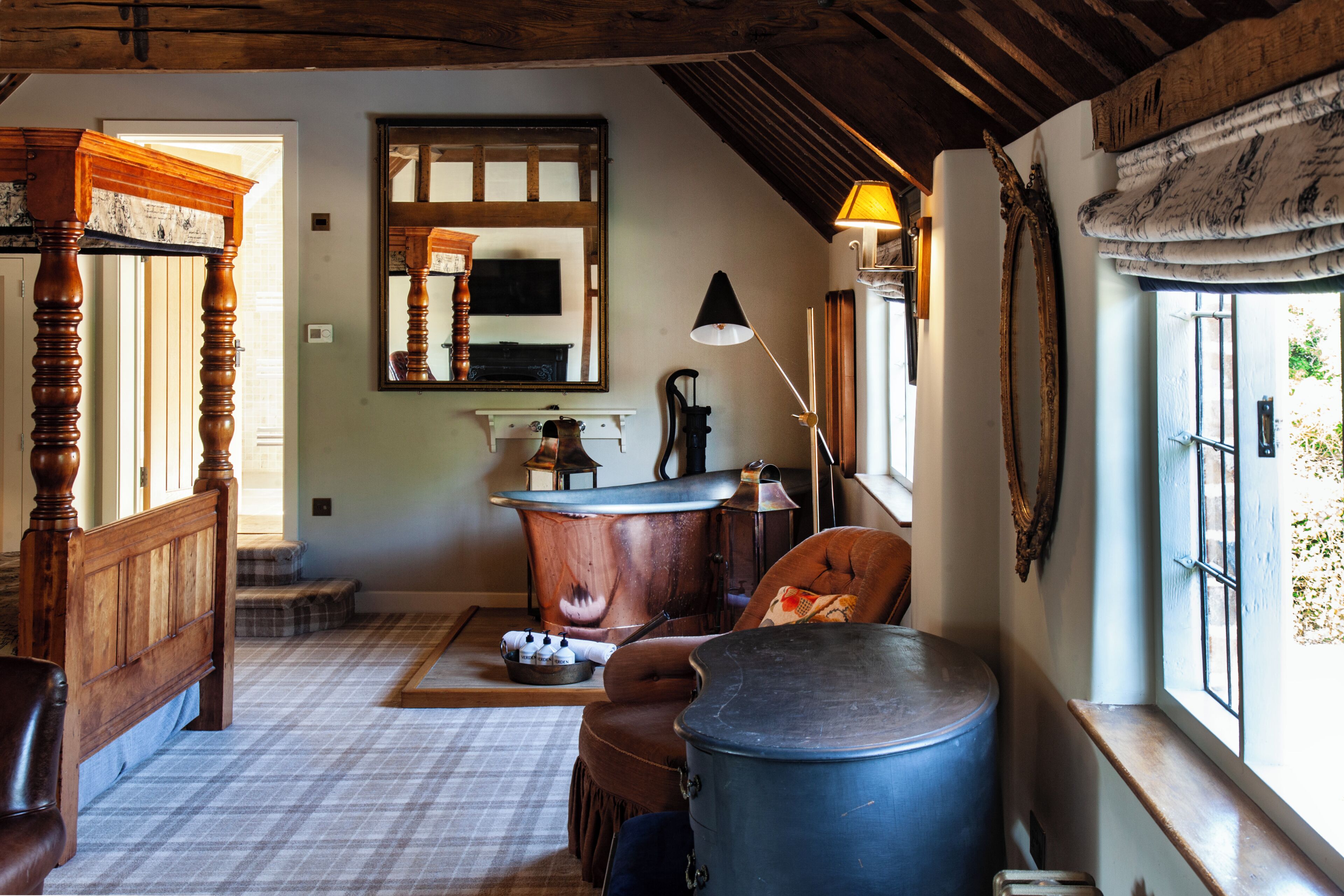 A room with a wooden bed, a large blue barrel, a fireplace, and a window with curtains.