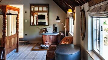 A room with a wooden bed, a large blue barrel, a fireplace, and a window with curtains.