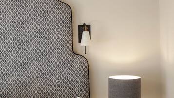 A bed with a patterned headboard, a bedside lamp, and a small drawer unit.