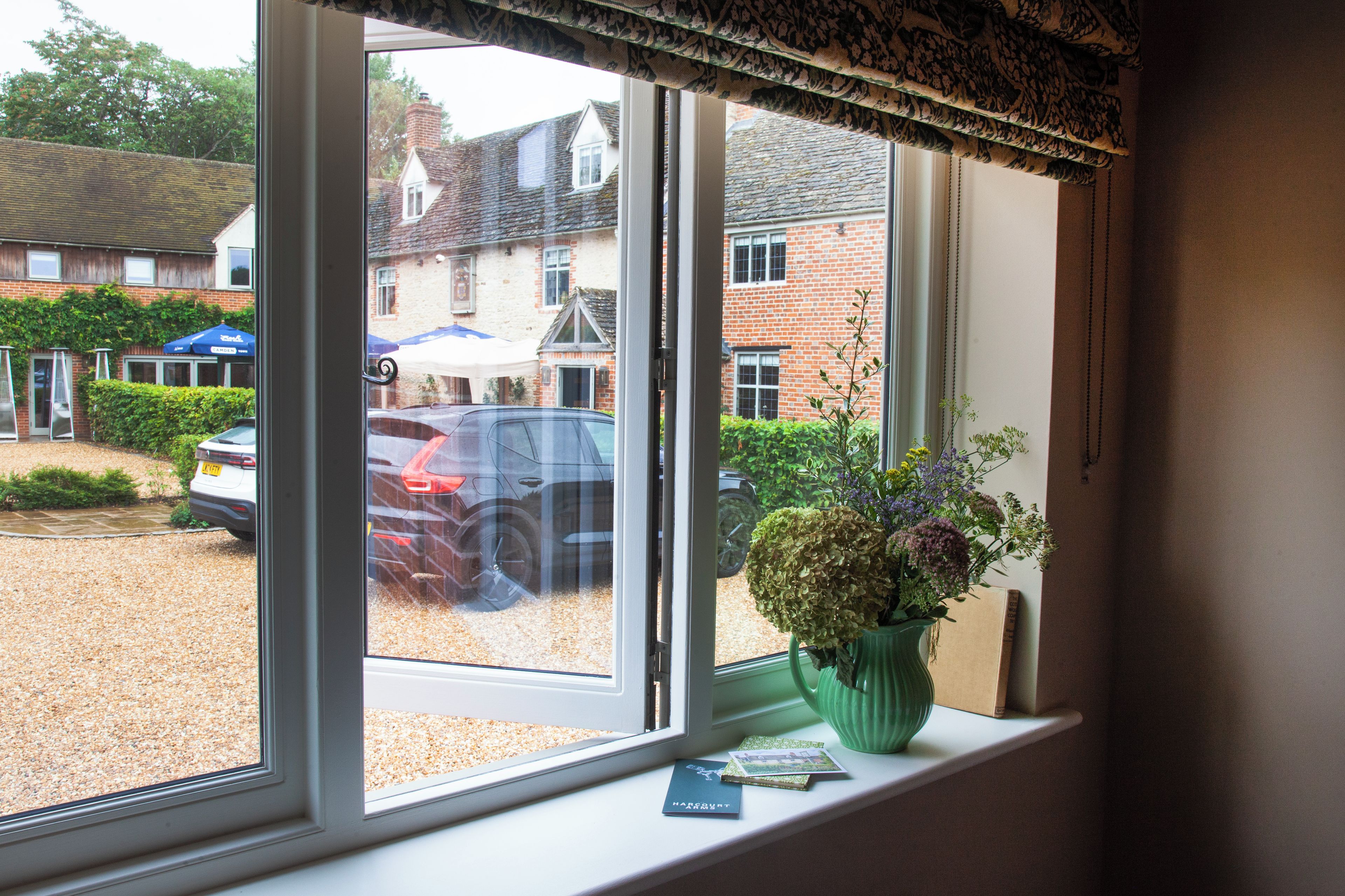 A window with a view of a parking area and a building with a brick facade.