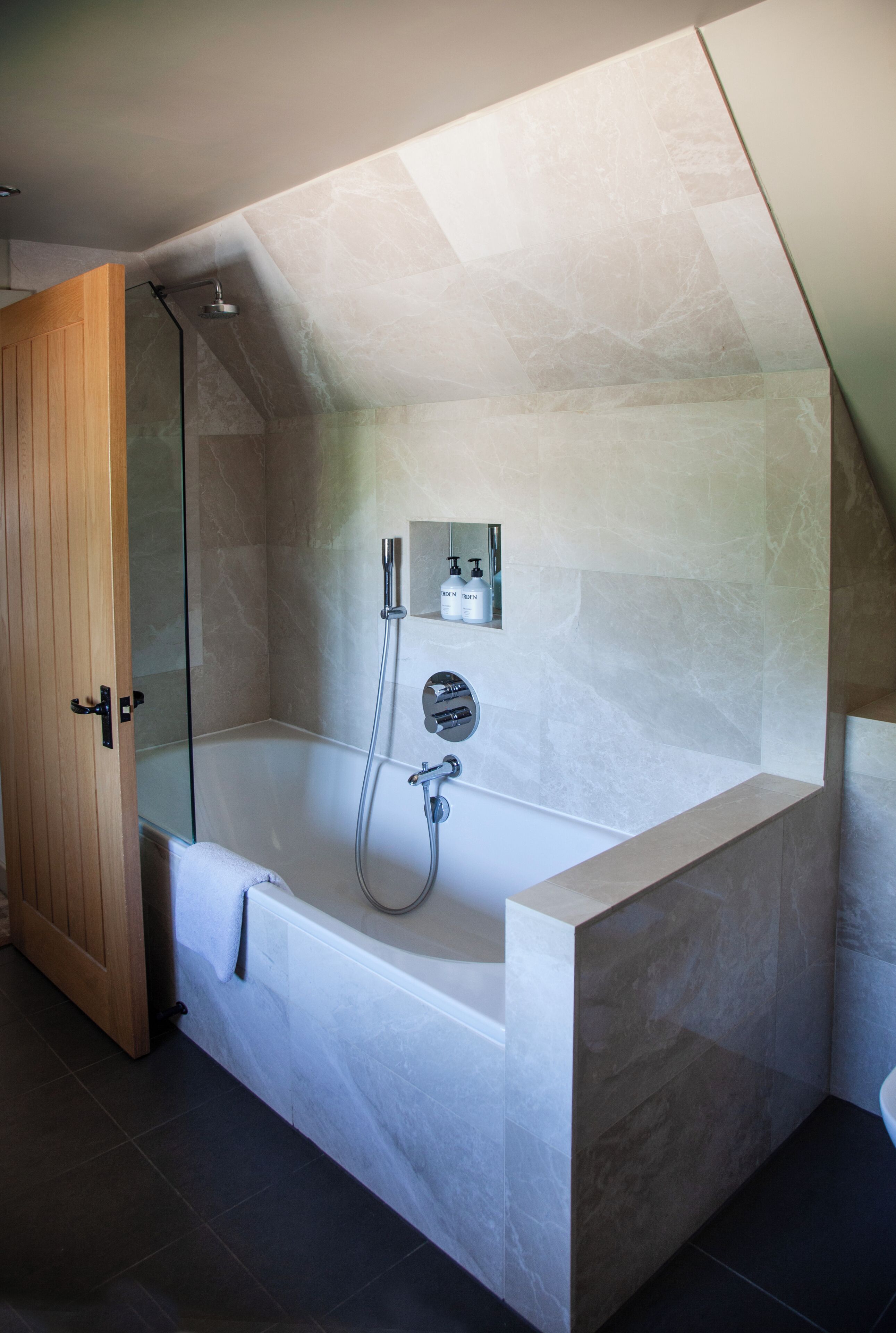 Ein modernes Badezimmer mit einer freistehenden Badewanne, einer Duschkabine aus Glas und einer Holztür.