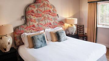 Une chambre d’hôtel avec un grand lit, deux lampes de chevet, une chaise et une fenêtre avec des rideaux.