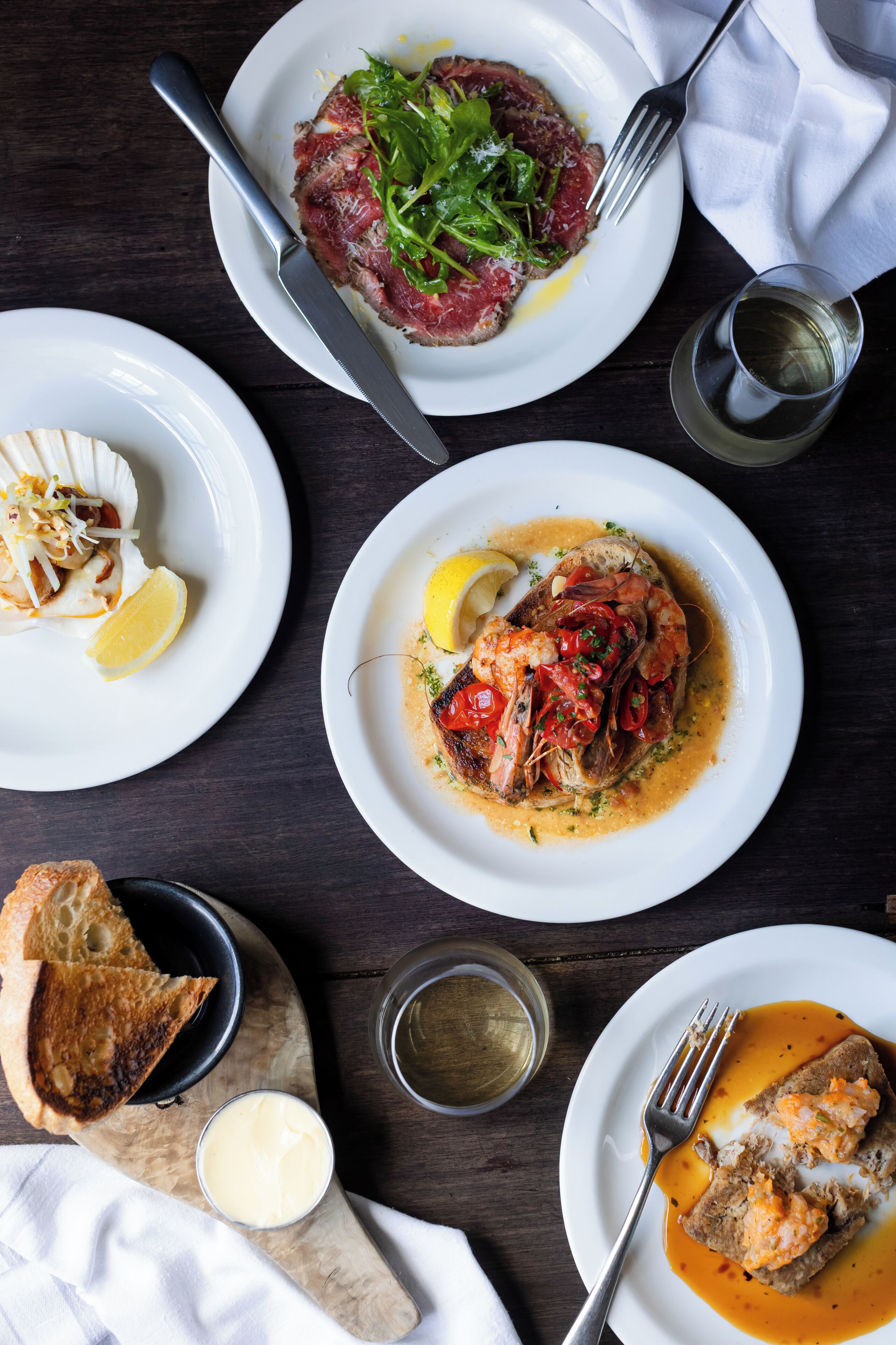 Une table à manger avec différents plats, notamment des fruits de mer et du pain.