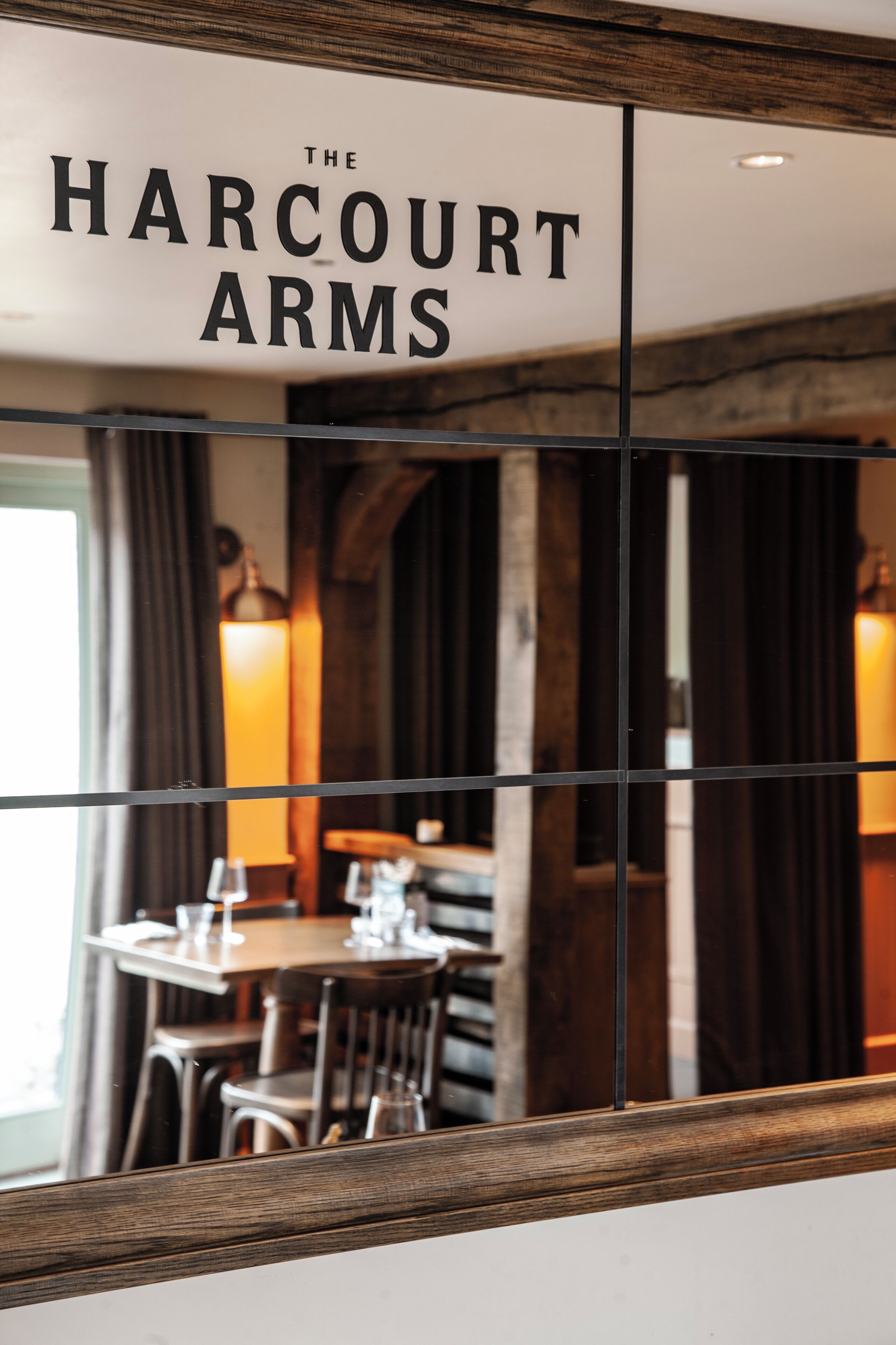 L’intérieur d’un restaurant, avec une table, des chaises et une enseigne indiquant « The Harcourt Arms ».