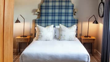 A hotel room with a large bed, two bedside tables, a headboard, a clock on the wall, and a window with curtains.