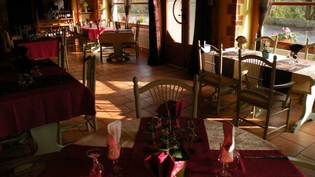 Ein gemütliches Restaurant mit Holztischen, einer Bar und großen Fenstern mit Blick ins Freie.