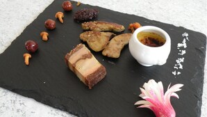 Ein Schiefer Serviertablett mit verschiedenen Speisen und einer Blumendekoration.