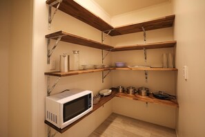 A compact kitchen with built-in shelves, a microwave, and various kitchenware. - Groovy on Grey - Spa Pool, Central, Sleeps 8 (Rotorua)