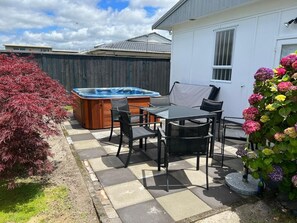 A patio area with a hot tub, outdoor furniture, and a potted plant.