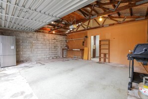 A spacious garage with a concrete floor, a metal roof, and a refrigerator.