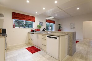 A modern kitchen with a central island, built-in appliances, and large windows with red valances.