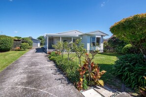 A residential house with a front porch, a driveway, and a well-maintained lawn. - Groovy on Grey - Spa Pool, Central, Sleeps 8 (Rotorua)