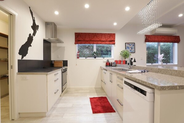 A modern kitchen with white cabinetry, a red rug, and a black island.