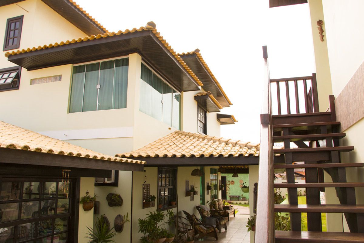 A two-story building with a tiled roof, a staircase, and outdoor seating area with chairs and potted plants.