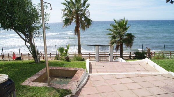 A patio with a view of the ocean, a metal fence, and palm trees. - Beachfront, overlooking the sea, Air conditioning. (Mijas Costa)