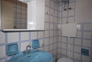 Casa de banho com lavatório azul, espelho e sanita.