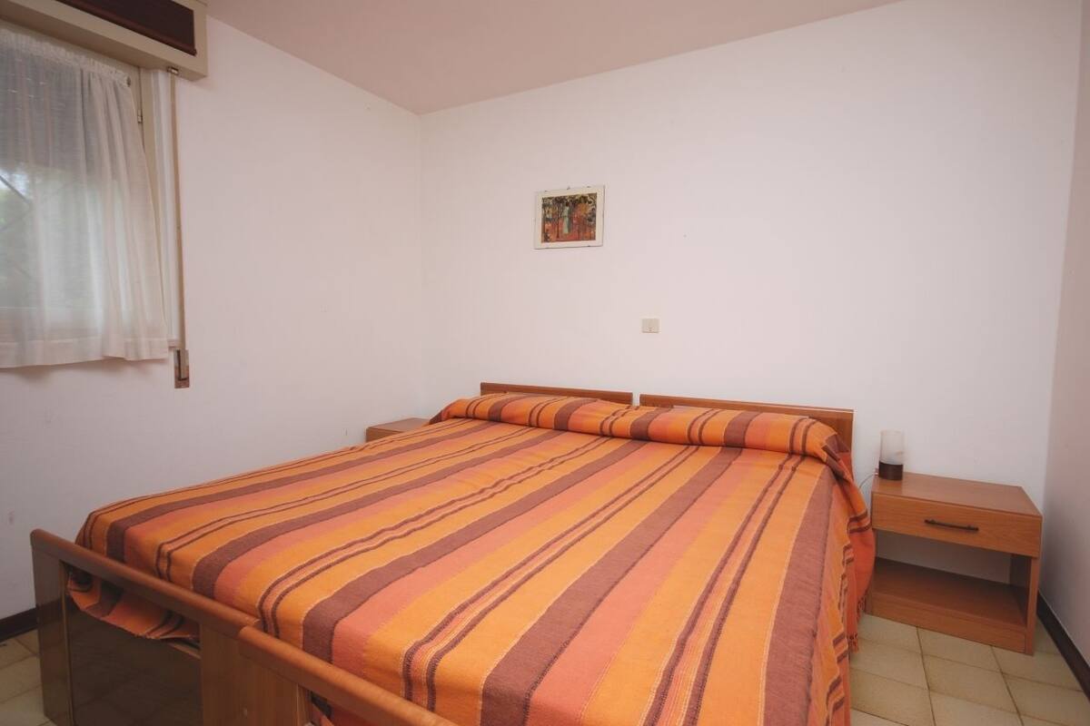 Habitación individual con una colcha a rayas, una mesita de noche y una pequeña lámpara de noche.