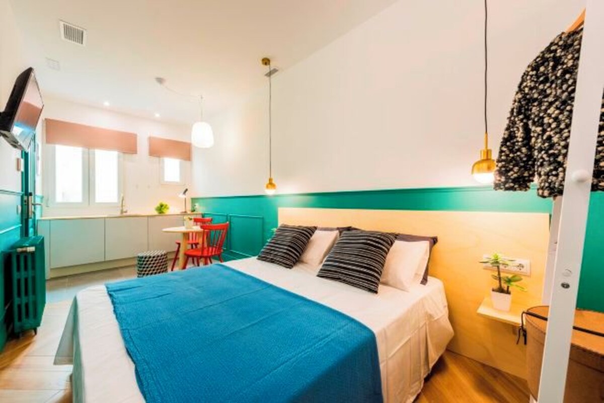 Una habitación de hotel pequeña con cama, mesita de noche y un pequeño escritorio.