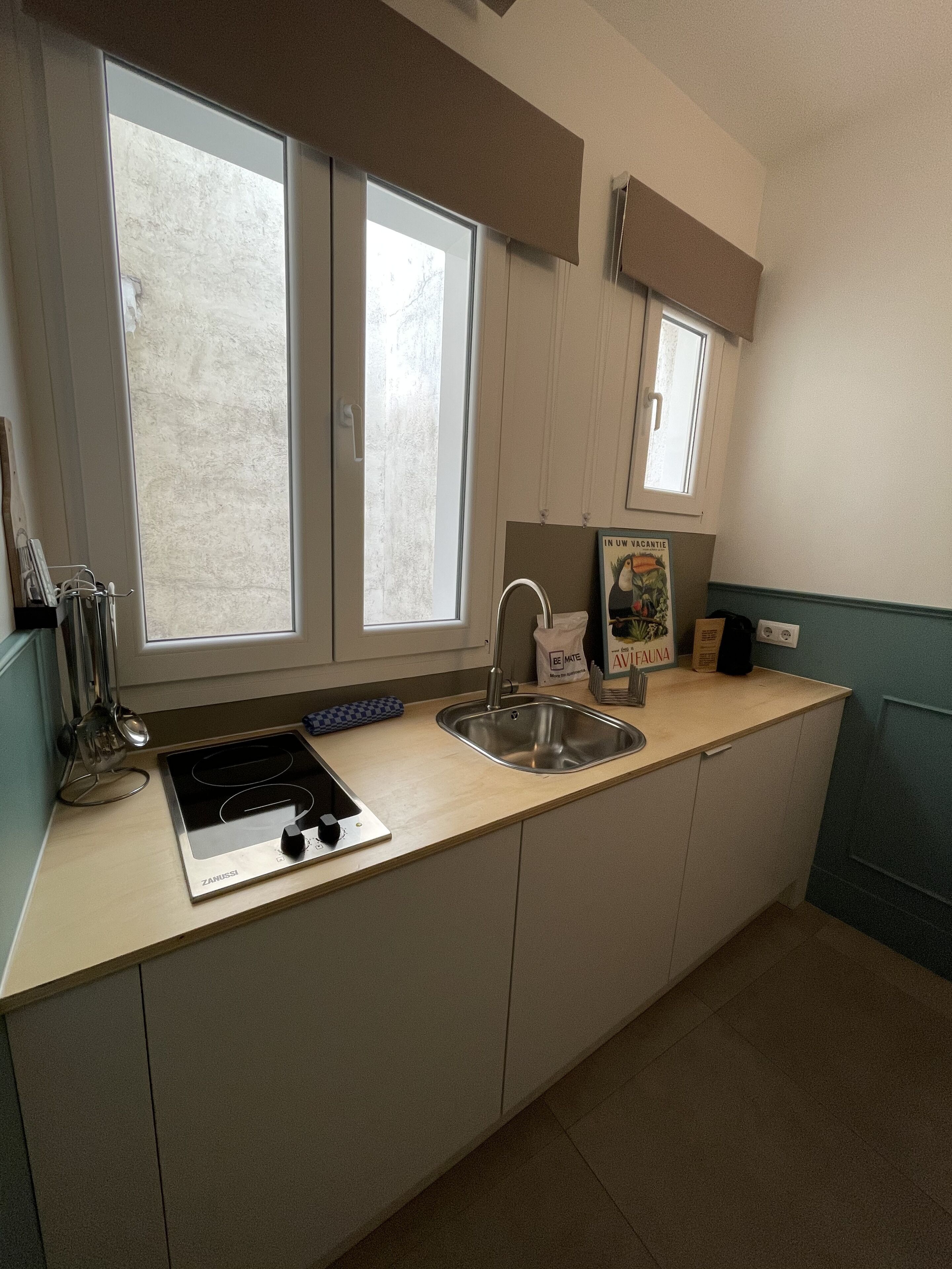 A compact kitchen with a built-in stove, a sink, and two windows.