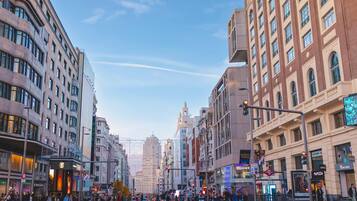 A city street with tall buildings, a clear sky, and a pedestrian crossing.
