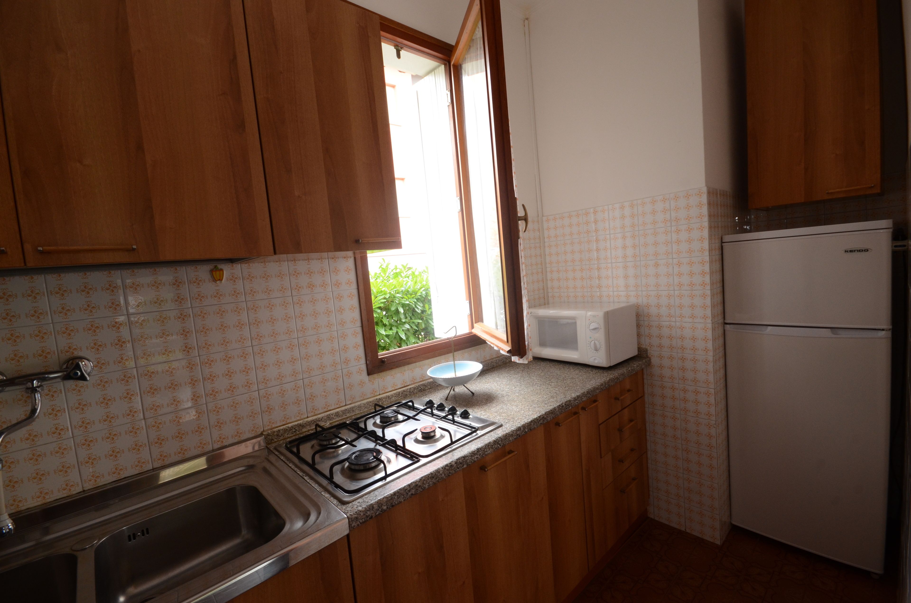 A kitchen with wooden cabinets, a gas stove, a microwave, and a refrigerator.