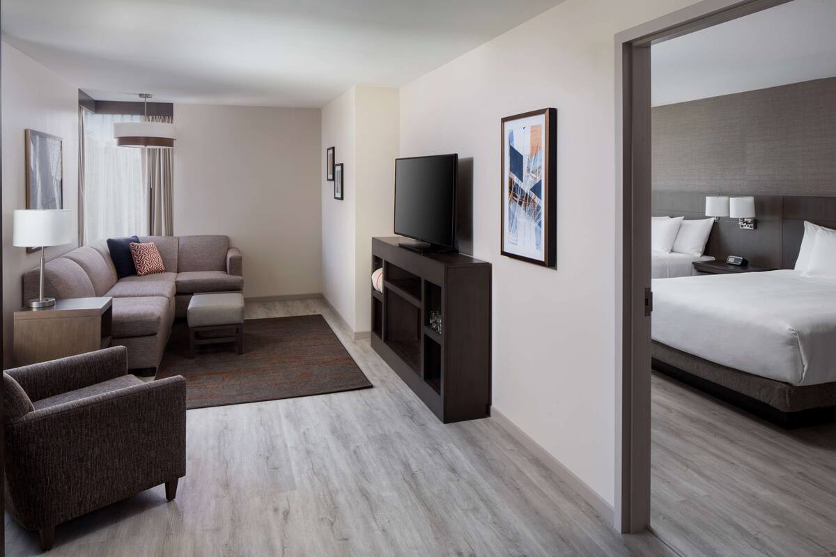 A hotel room with a sofa, a TV, a bed, and a small desk.