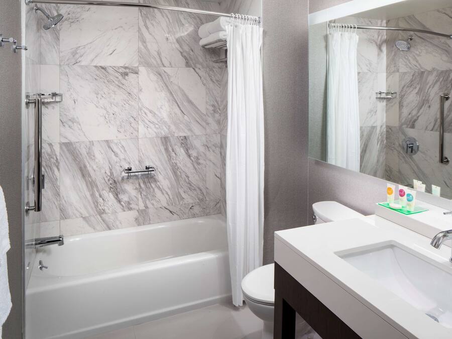 A modern bathroom with a glass-enclosed shower, a white bathtub, and a vanity with a sink and mirror.