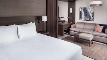 Una habitació d'hotel amb un llit gran, un escriptori, un sofà i una taula petita.