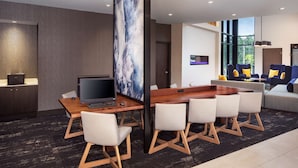 Habitación de hotel moderna con un escritorio de madera, un televisor de pantalla plana y un cuadro abstracto de gran tamaño. Cuenta con un sofá y una mesa de centro en la zona de estar.